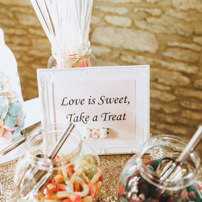 A sign that says "love is sweet, take a treat" on a pick and mix station