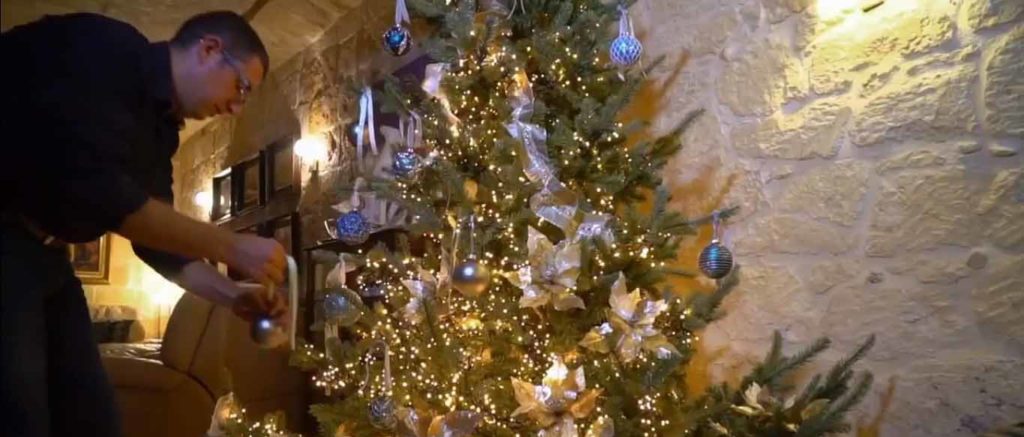 A person decorating a green Christmas tree