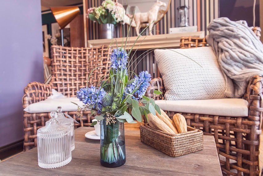 A vase with blue fresh flowers on a coffee table