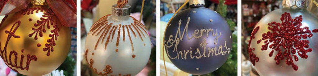 Four hand crafted baubles with different glittered designs and colours