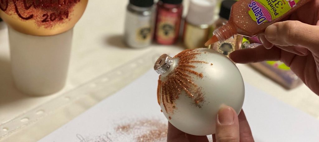A person creating a personalised bauble with rose gold glitter