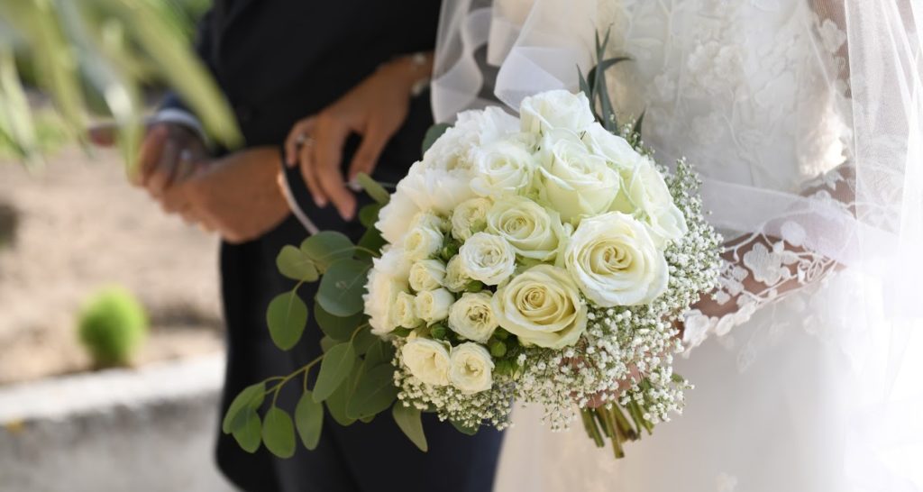 A bride walking with her dad while holding an all white bridal bouquet