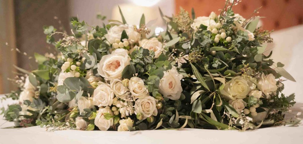 A bridal bouquet and two bridesmaids' bouquets sitting on the bed