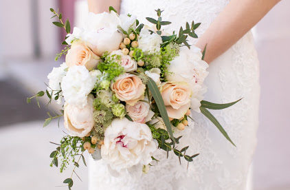 A small bridal bouquet with cream roses, light pink flowers and green foliage.