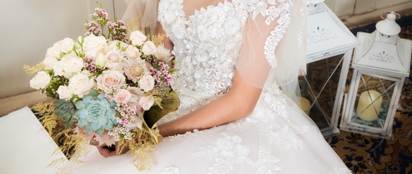 A bride sitting with a beautiful neutral bridal bouquet with a touch of pinks and blues utilizing succulents.