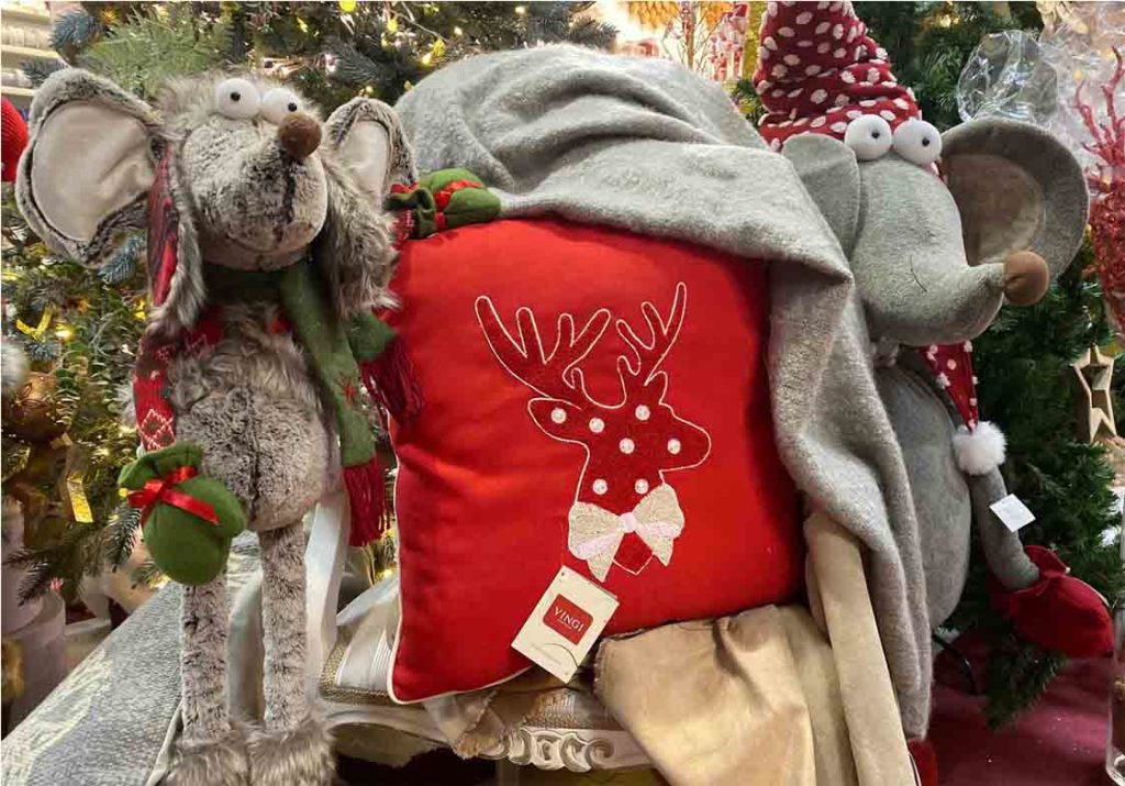 A Christmas plush toy near a Christmas pillow.