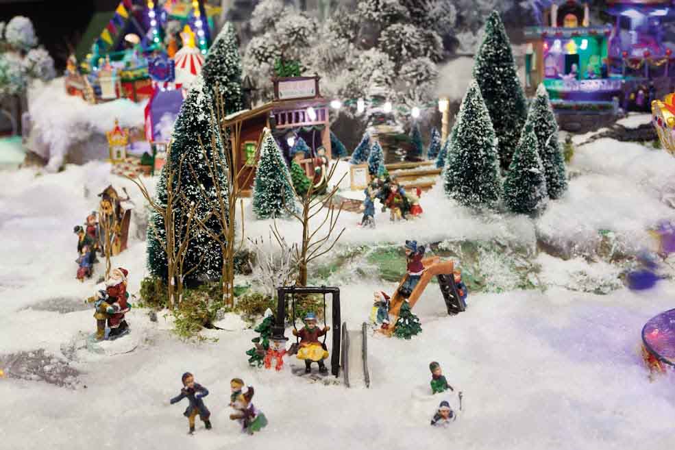 Kids running around in snow part of a huge Christmas village.